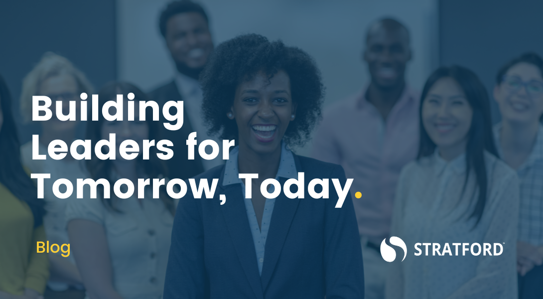 Young, confident female leader standing in the forefront surrounded by diverse group of colleagues. Title of blog superimposed over image.
